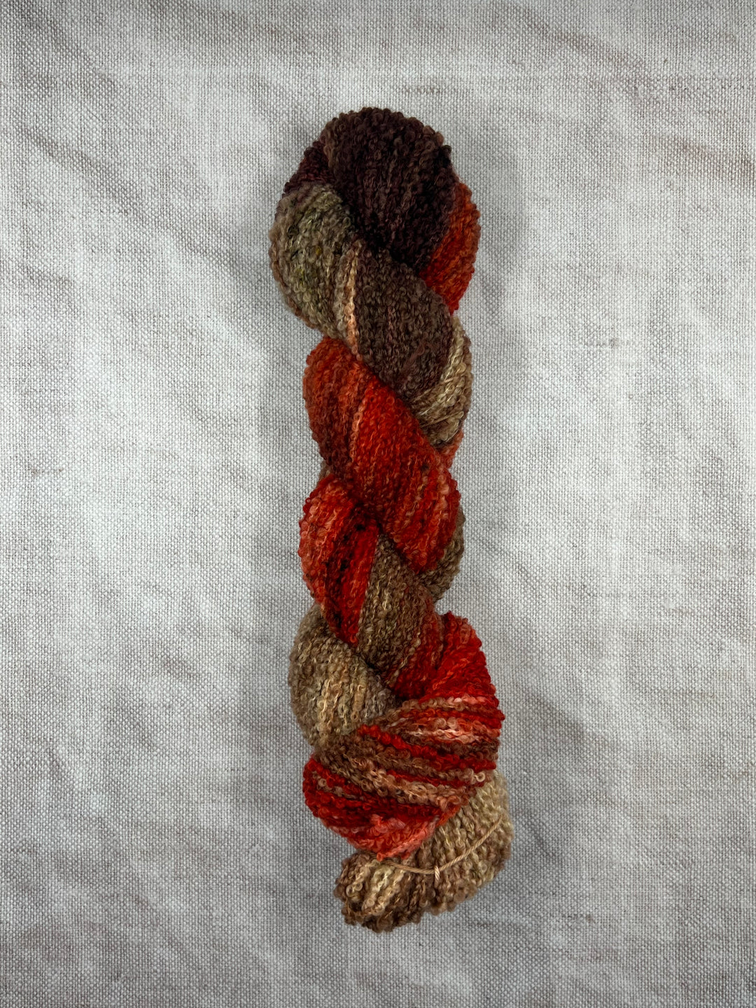 Boucle yarn in red, brown, beige and green.